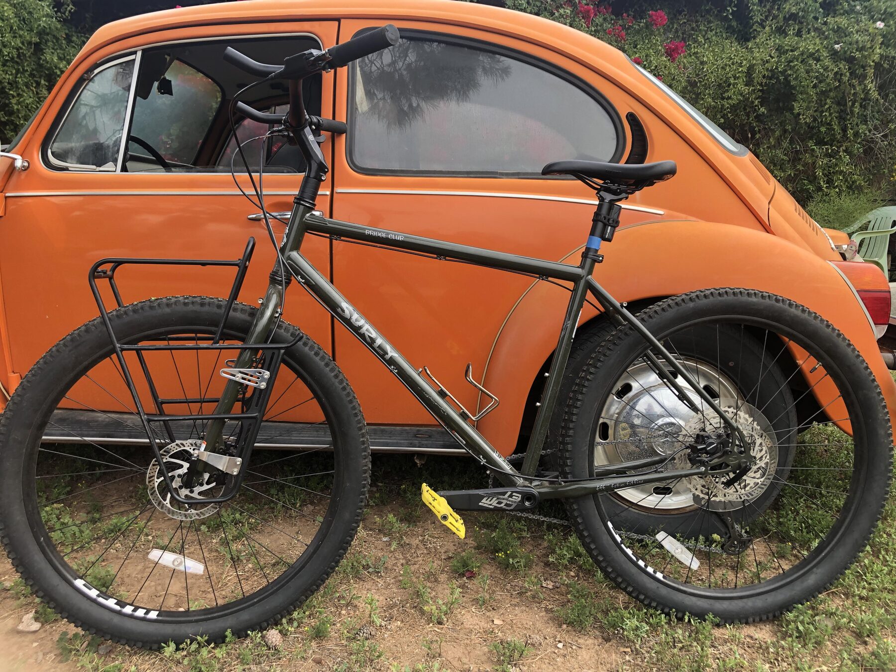 A Surly Bridge Club fitted with Velo Orange Crazy Bars on a tall black stem, parked against an orange Volkswagen Beetle